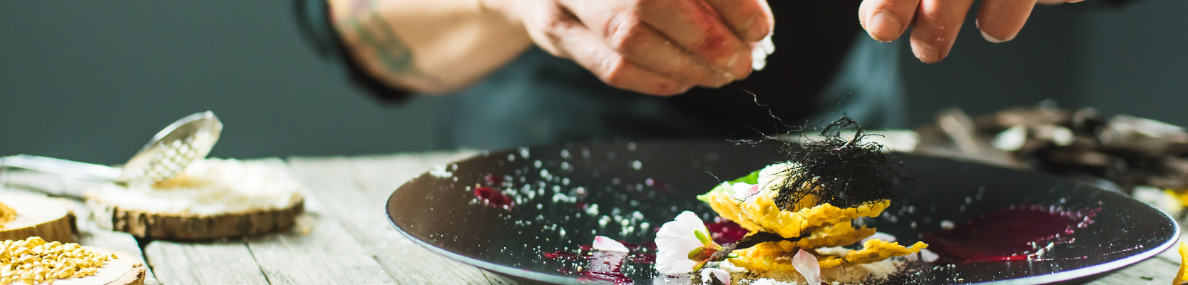 Essen auf schwarzem Teller mit Händen über dem Teller.