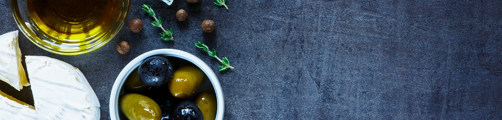 Oliven, Olivenöl und Käse auf dunklem Untergrund