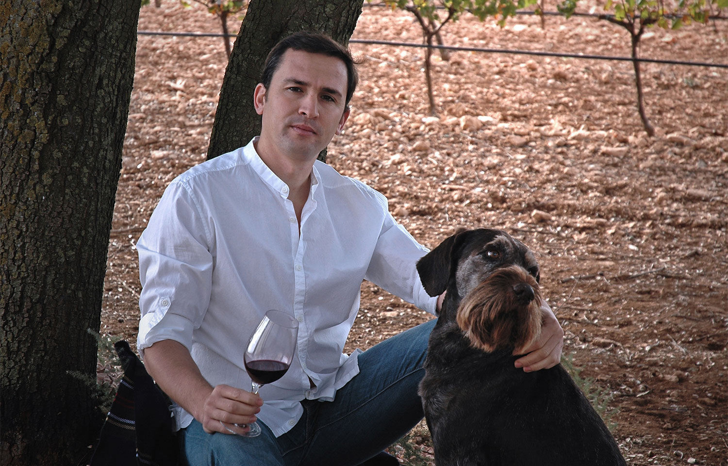 Winzer Pedro Huerta mit Rotweinglas und Hund.