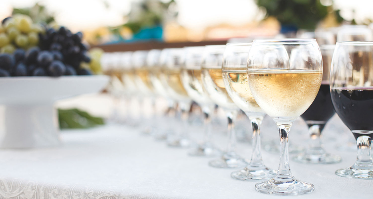 Weingläser gefüllt mit rotem und weißem auf einer weiß gedeckten Tafel. 