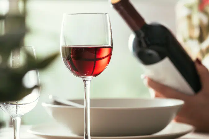 Rotweinglas mit Bordeaux-Flasche im Hintergrund