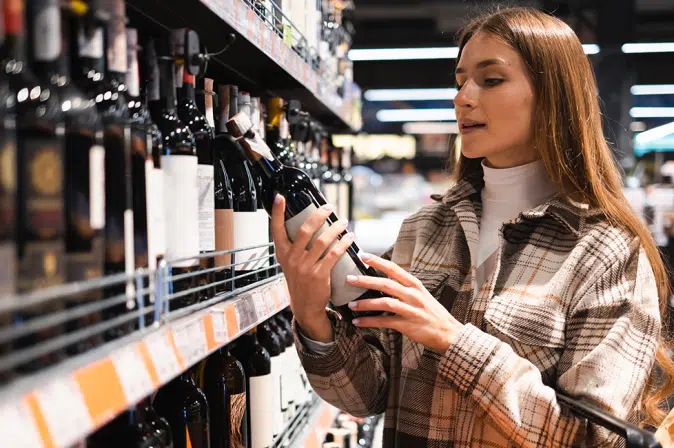 Frau im Supermarkt am Weinregal